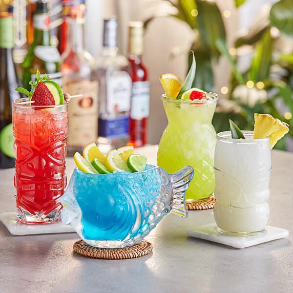 A group of blue drinks in Acopa fish shaped cocktail glasses.