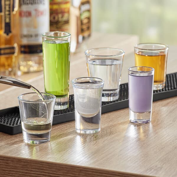 A table with several Acopa 1 oz. Shooter Glasses filled with purple liquid.