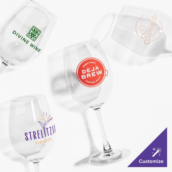A group of clear Acopa Select wine glasses with orange custom writing.