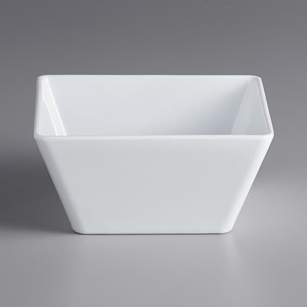 An Acopa Rittenhouse white square melamine bowl on a gray surface.