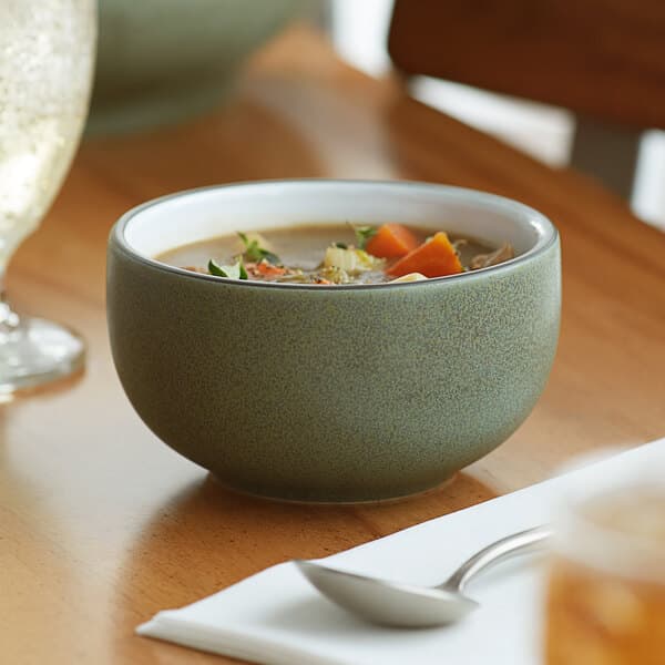 An Acopa Embers moss green stoneware bowl filled with soup on a table.