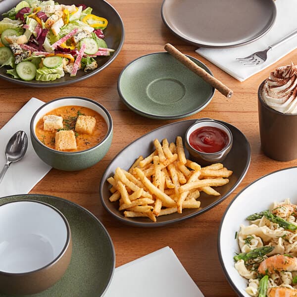 A table with Acopa Moss Green Matte stoneware bowls filled with pasta, red sauce, and soup.