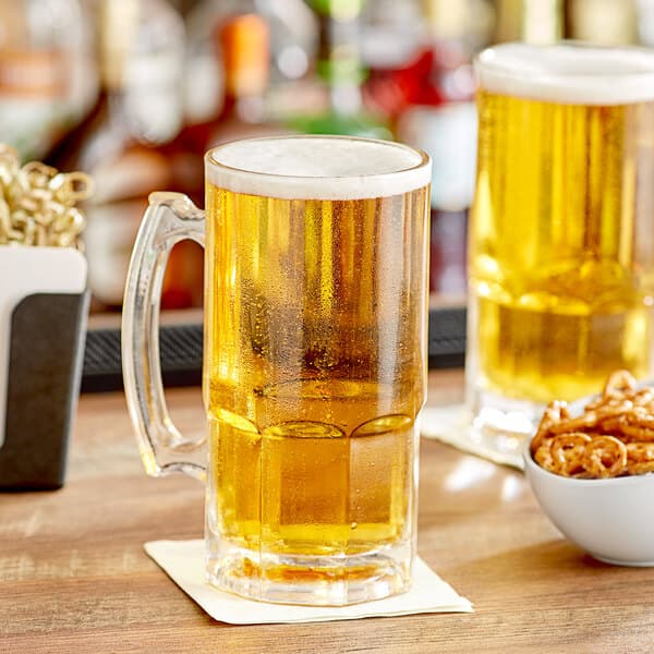 An Acopa beer mug filled with beer on a table with a bowl of pretzels.