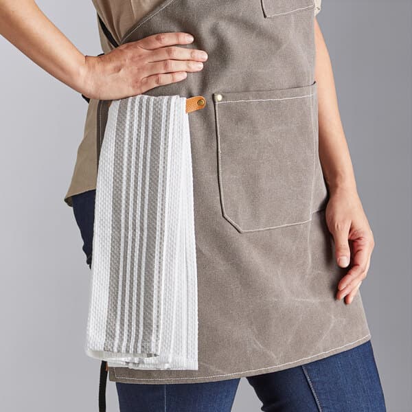 A woman wearing an Acopa Hazleton canvas cross-back bib apron over a white towel.