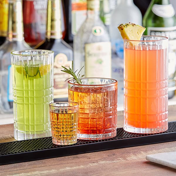 A row of Acopa Madras Beverage Glasses filled with different colored drinks on a bar.