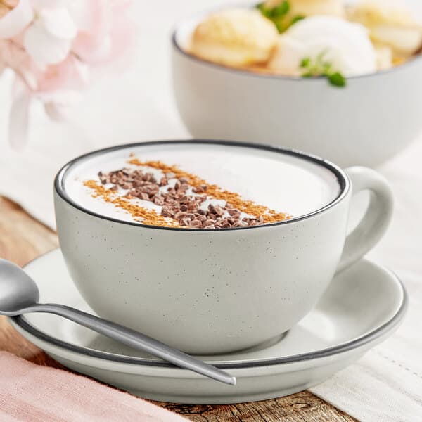 A grey matte stoneware cup of coffee with a spoon and ice cream in it.