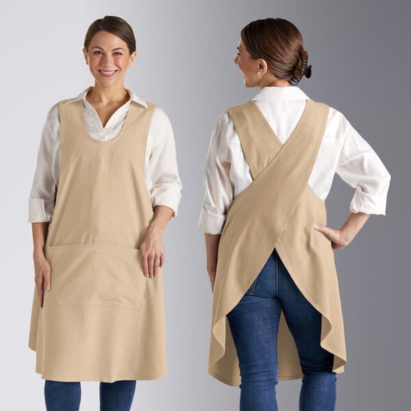 A woman wearing a tan Acopa smock bib apron with pockets.