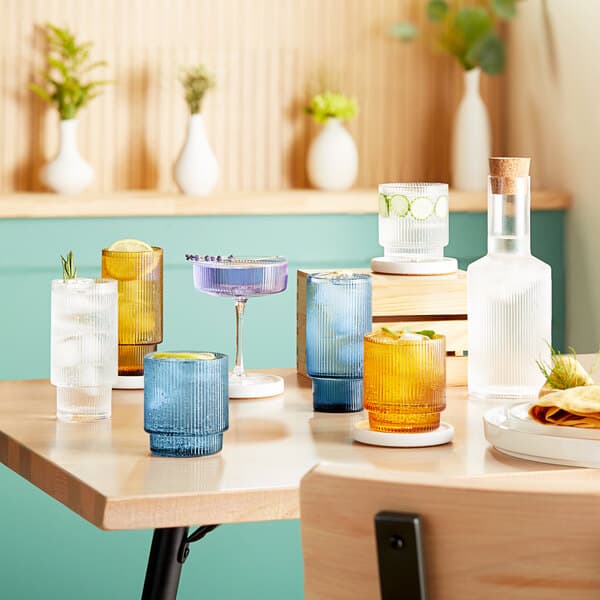 A table with a variety of drinks in Acopa Lore amber highball glasses.