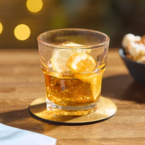 An Acopa Memphis rocks glass with a drink, ice, and a lemon slice.