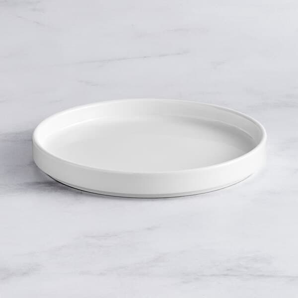 An Acopa Lore bright white porcelain plate on a marble surface.