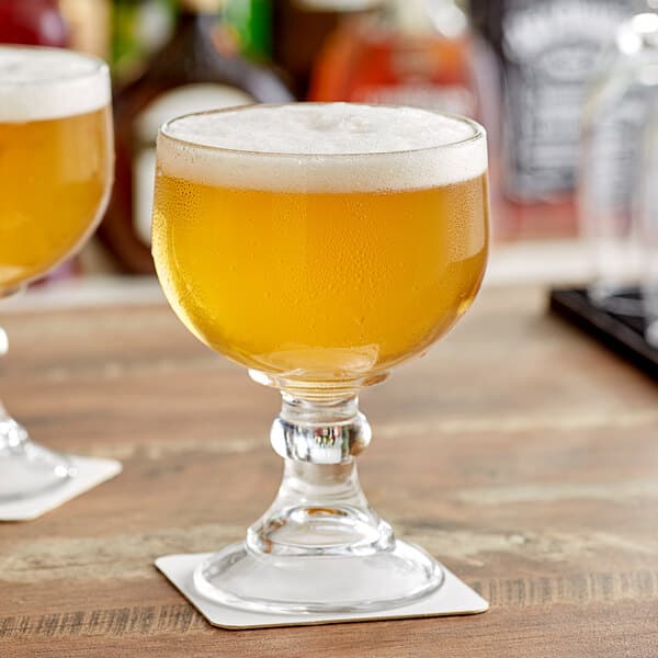 Two Acopa schooner glasses filled with beer on a table.